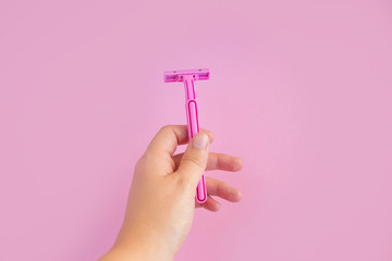Pink women's razor on a pink background