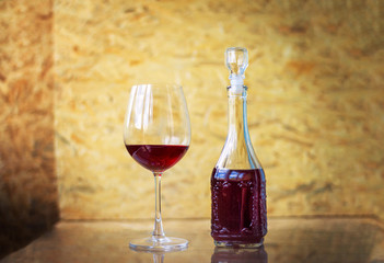 Red wine in a glass and in decanter on a table over wooden background. Homemade alcohol drink. 