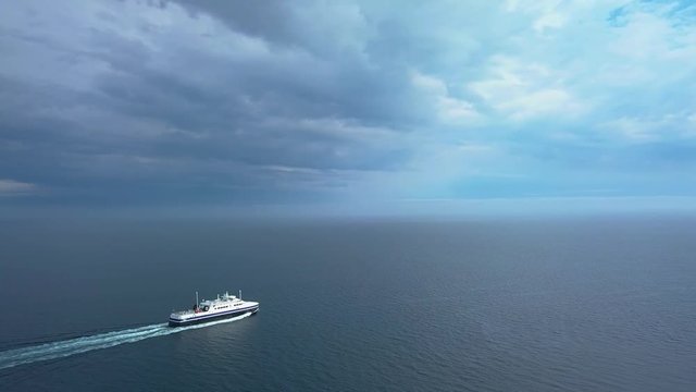 The ferry sails across the ocean, in the background the storm sky. Norway. 4K
