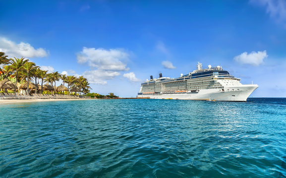 Cruise ship docked at tropical island on sunny day