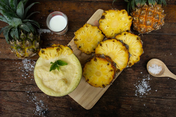 Pineapple juice and pineapple slices cut into pieces on a wooden table. Healthy wood fiber helps to reduce food. Pineapple juice Contains fresh milk, nectar and salt.