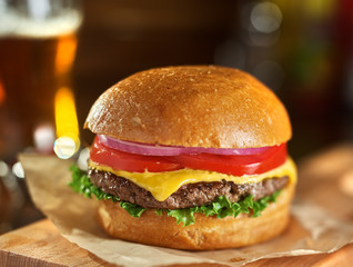 tasty cheeseburger with beer in background - obrazy, fototapety, plakaty