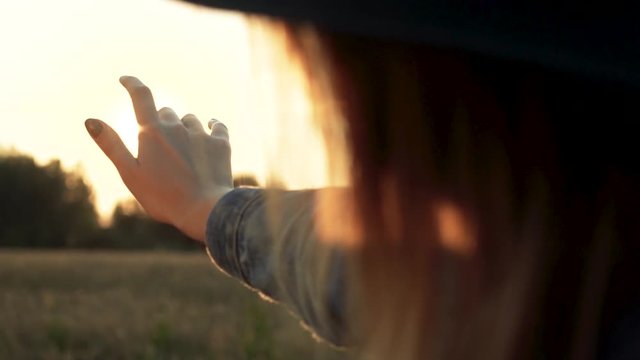 In this beautiful and cinematic slow motion close up footage you can see romantic hippie woman playing with sun rays during evening sunset. She is trying to catch the sun into palm with her fingers.