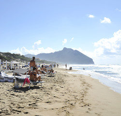 Relaxed people on the Sabaudia beach for the summer holidays. The Circeo Mountain on the...
