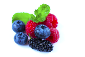 Close-up arrangement mixed, assorted berries including blackberries, strawberry, blueberry, raspberries and fresh leaf on white