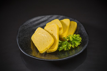 Tamako Sashimi, Sweet Egg served on traditional Japanese food on ceramic dish, Japanese food style, Sushi Bar Menu on black background, selective focus 