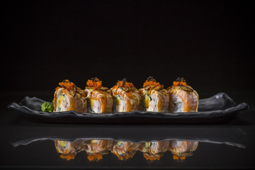 Salmon Roll topped Foie Gras Roll and sweet sauce served on traditional Japanese food on ceramic dish, Japanese food style, Sushi Menu, salmon sushi roll on black background, selective focus