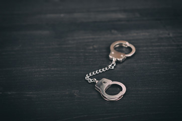 Handcuffs on a black wooden background.