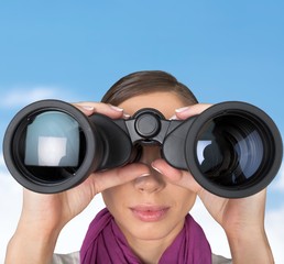 Girl looking into binoculars on light background