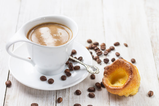 A cup of hot coffee with a yorkshire pudding on a white wooden background. Breakfast. Copy Space.