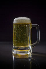 Cold Craft light Beer in a glass with water drops, Mug of beer on black background, Glass of cold light beer with foam, Mug of beer frosty with bubble froth
