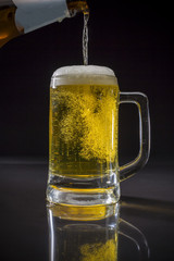 Pouring beer, Pint glass with beer on black background, Glass of cold light beer with foam