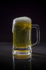 Mug of beer Overflowing on black background, Glass of cold light beer with foam, Pint glass
