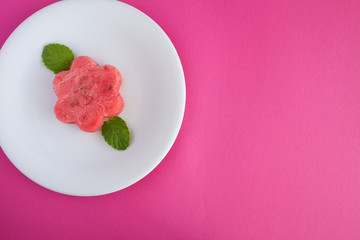 Watermelon flower in the white  plate  on the pink  background.Top view.Diet minimal concept.Copy space.