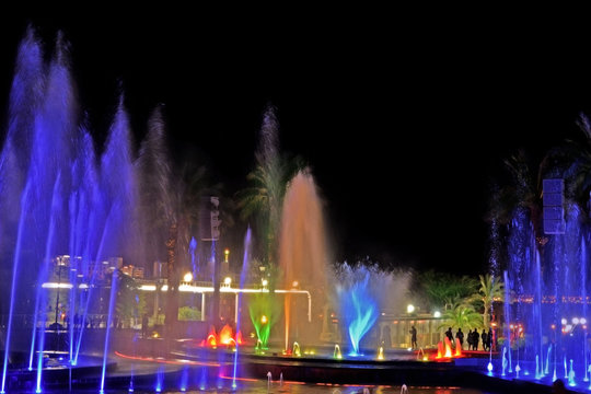 A glowing musical fountain at night. Splashes of colored water.