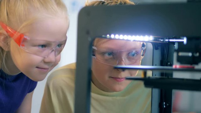Children printing robot part on a 3D printer. 4K.