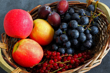 Naklejka na ściany i meble Choice of summer fruits in market basket on dark board, high angle view