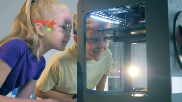 Pupils, schoolchildren look at 3d printer. Back to school concept.