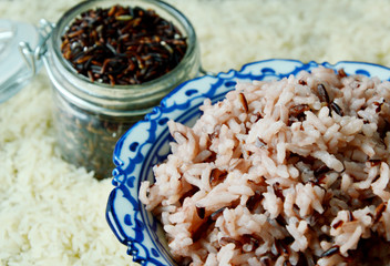 Cooked Riceberry mixed with white rice and uncooked Rice background.