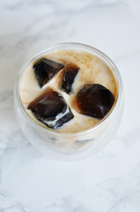 glass cup of coffee with ice cubes and milk