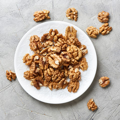 Walnut kernels on white plate over gray background.