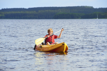 Active happy child. Teenage school boy having fun enjoying adventurous experience kayaking on the lake on a sunny day during summer vacation