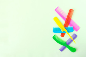 Many different multi-colored plastic hair comb crest brushes isolated on light green pastel background. Mininmalistic feminine hairdresser stylist concept. Flat lay, top view, copy space