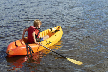 Active happy child. Teenage school boy having fun enjoying adventurous experience kayaking on the lake on a sunny day during summer vacation