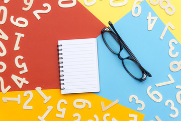 notebooks and glasses in the center of colorful paper and scattered numbers