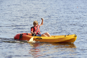 Active happy child. Teenage school boy having fun enjoying adventurous experience kayaking on the lake on a sunny day during summer vacation