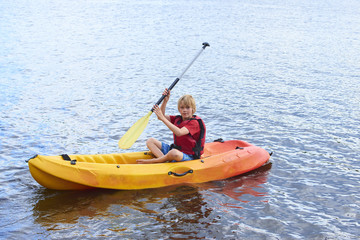 Fototapeta na wymiar Active happy child. Teenage school boy having fun enjoying adventurous experience kayaking on the lake on a sunny day during summer vacation