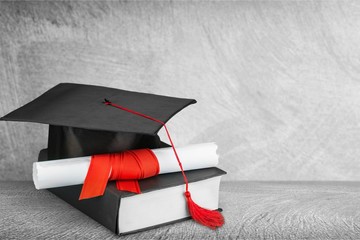 Graduation mortarboard on  book on background