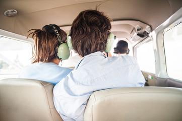 Young tourist couple taking a small plane.  Wearing headsets and being affectionate with eachother during the flight.