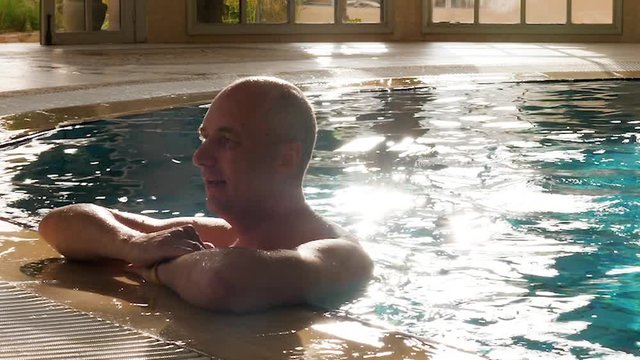Portrait adult man relaxing in swimming pool near edge in luxury hotel