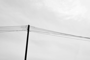 alone wooden pylon with wires in rural - monochrome