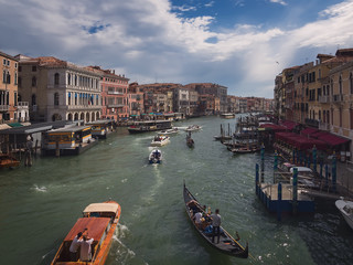 Fototapeta na wymiar Canal de Venecia, arquitectura historica y numerosos turistas paseando en barco o gondola. Vista de la ciudad desde el puente de Rialto