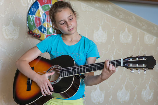 Teen girl with guitar at home.