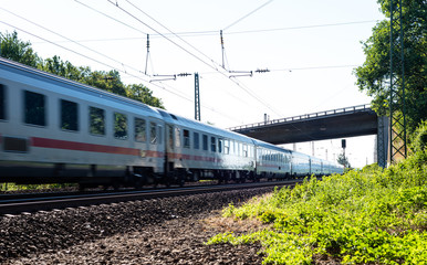 Obraz premium A moving railway train under the viaduct on a summer sunny day in western Germany.