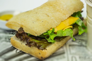 Close up of a fresh burger with home-made bread with spices and olives, red and green salad and a bowl of sauces, ketchup, mustard and mayonnaise. Shallow depth of focus.