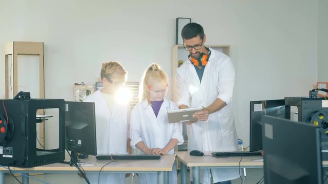Kids studing modern technology in a laboratory with a school teacher. 4K.