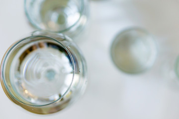 Close-up of blurry glasses of crystal clear drinking water on a white table. Shallow depth of focus. Health concept from nature.