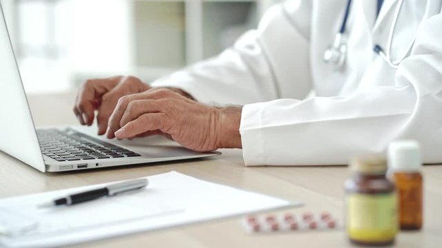 Male doctor typing on computer
