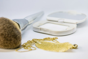 Close-up of a compact transparent face powder and brush. Shot on a white background. Shallow depth of focus.  Concept beauty fashion.
