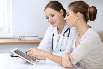 Doctor and patient having a pleasure talk while sitting at the desk at hospital office. Healthcare...