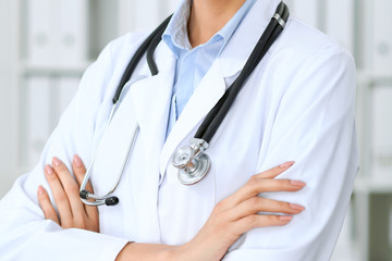 Closeup of doctor woman standing with arms crossed at hospital.  Health care, insurance and help concept