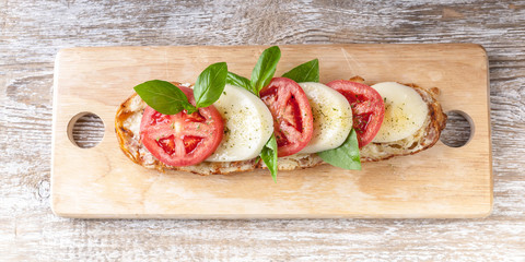Sandwich with tomatoes, mozzarella, basil leaves and spices. Top view