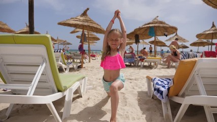 Happy girl teenager practising yoga asana on summer beach at sea background