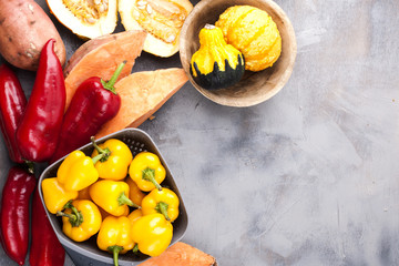 Sweet pepper yellow and red, potatoes and pumpkin on a gray background. The harvest is autumnal. Free space for text, frame. Top view