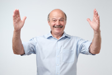 Handsome mature man gesturing with hands showing big and large size sign, measure symbol.