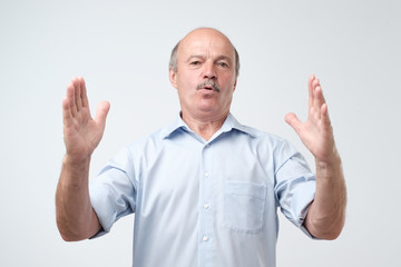 Handsome mature man gesturing with hands showing big and large size sign, measure symbol.